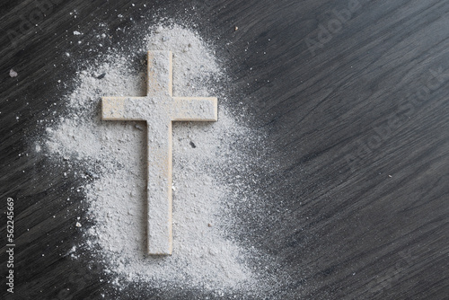 Cross covered in ashes on a dark wood background with copy space