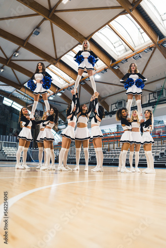 Full shot of a cheerleading squad doing three extension stunts at the same time. Sport concept. Vertical photo. High quality photo