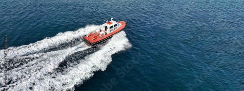 Aerial drone ultra wide photo of red pilot boat cruising in high speed in Mediterranean deep blue sea offering navigational aid to ships