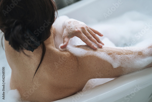 Crop photo of self loving adult brunette woman taking bath with foam at home