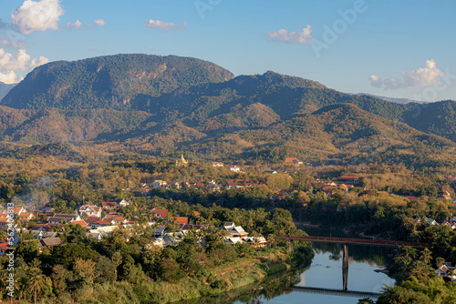Scenery view small town of Luang Prabang city center surround big mountain and Mekong river, Cityscape in the evening with golden sunlight during sunset, The ancient capital province in northern Laos.