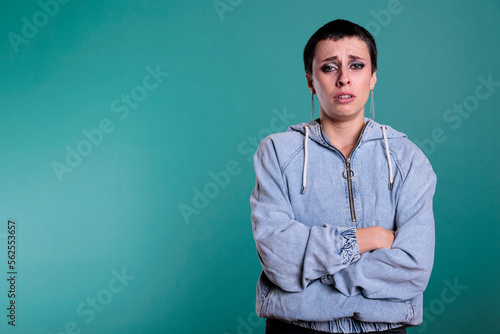 Portrait of sad unhappy woman standing with arm crossed while crying in studio with isolated background, person having negative emotion. Emotional female looking at camera with grief expression