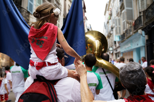 Petite fille sur les épaules de ses parents au défilé des bandas des Fêtes de Bayonne