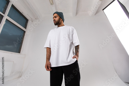 Stylish african american man in a white t-shirt stands in the studio on a white background.