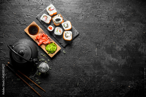 Delicious rolls with salmon and vegetables on a stone Board with soy sauce in bowl.