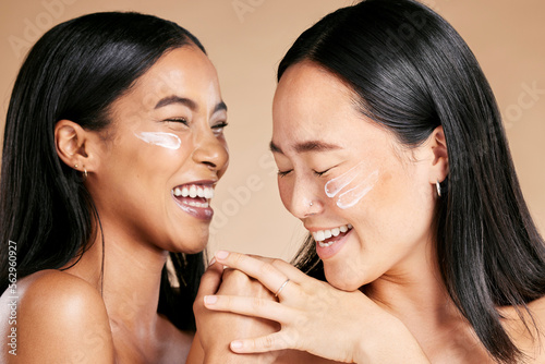 Happy, beauty and skincare women with cream for face isolated on a beige studio background. Wellness, smile and Asian model friends with sunscreen for love of cosmetics and dermatology on a backdrop