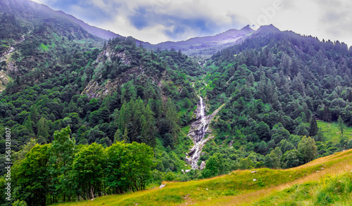 Panorama con cascata tra i boschi e le montagne in Val Sermenza. Valsesia. Alpi Italiane. Italia