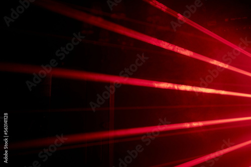 Bright red neon laser lights illuminate the darkness creating lines and triangle shapes in sci-fi effect.