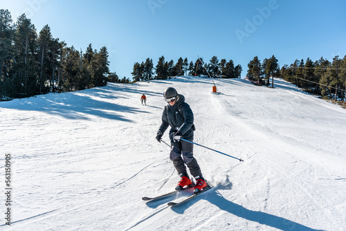 Two boys skiing down a large ski slope.