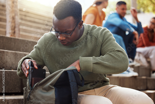 University, student and black man looking in bag at campus for learning, studying or lost knowledge book. College steps, scholarship and male checking or searching backpack for missing item outdoors.