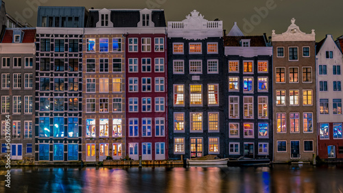 Amsterdam at night with dancing colorful houses at the Amsterdam canals in the Netherlands.