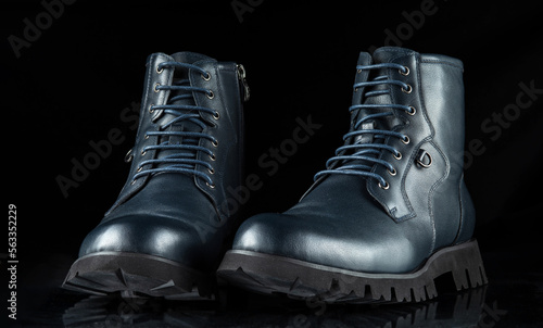 A pair of dark blue men's boots on a black background.