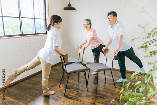 介護施設で椅子体操・運動・リハビリするシニア・高齢者の男女と理学療法士・介護士・トレーナー（脚） 
