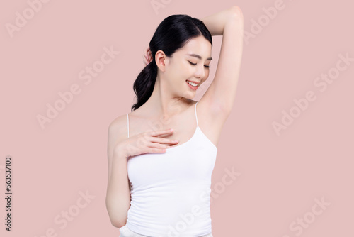 Beautiful young Asian woman lifting hand up to shows off clean and clear armpit or underarms isolated on pink background, Smooth and freshness armpit concept.