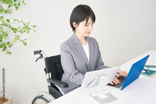 オフィスで車椅子に乗って働く障害者のビジネスウーマン