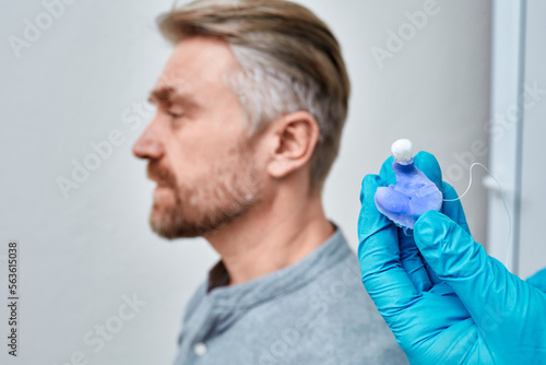 Audiologist holding molded individual earmolds for hearing aids of patient in hand, close-up. Custom earmolds for hearing aid