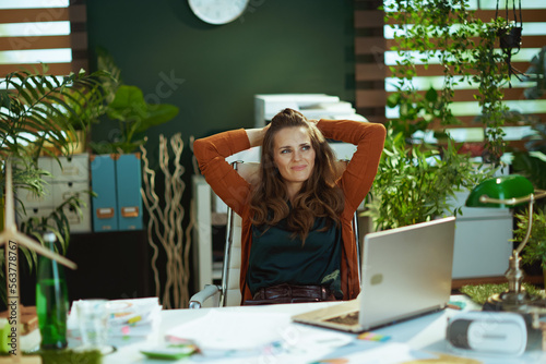 relaxed business owner woman in green office using laptop