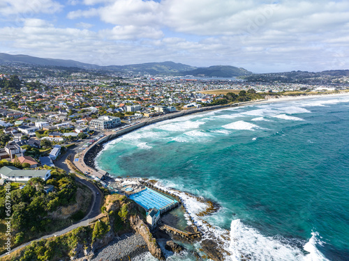 Beautiful high angle aerial drone view of a hot salt water pool in St Clair, a beachside suburb of Dunedin, the second-largest city in the South Island of New Zealand. Dunedin city in the background.