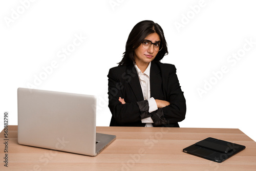 Young indian woman in a table with a laptop and tablet isolated suspicious, uncertain, examining you.