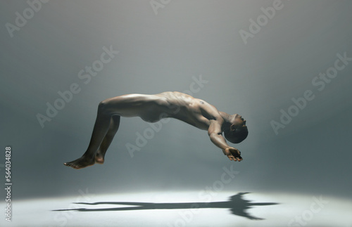 Float, man and naked model in a white background studio for creative art with shadow. Isolated, floating and nude body of a african male in the air with light showing artistic and erotic projection