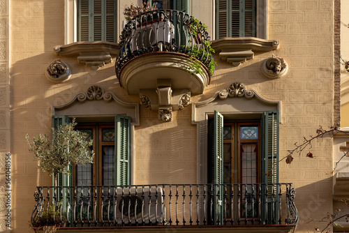 The facade of the urban historic building front view with open balconies and wooden shuttered windows in the morning, Barcelona, Spain