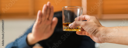 Alcoholism, sad depressed asian young man refuse, push alcoholic beverage glass, drink whiskey, sitting alone at night. Treatment of alcohol addiction, having suffer abuse problem alcoholism concept.