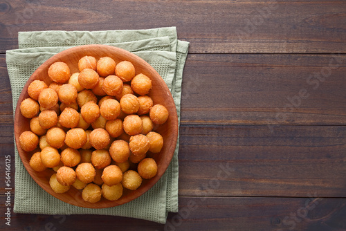 Fresh round baked Duchess potatoes or croquettes on wooden plate, photographed overhead on dark wood with copy space on the side (Selective Focus, Focus on the potato balls).