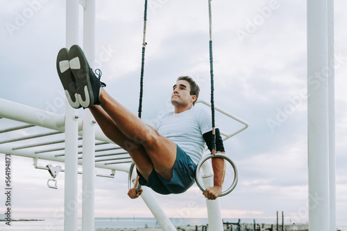 Athletic man doing functional training exercises at the outdoor gym - Sportive adult wearing sportswear training outdoors, workout at gymnastics bar - Sport, healthy lifestyle and fitness concepts