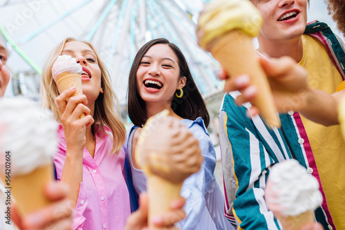 Multiracial young people together meeting at amusement park and eating ice creams - Group of friends with mixed races having fun outdoors - Friendship and lifestyle concepts