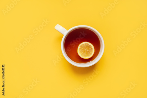  black lemon tea in a large cup on a yellow background with a yellow blanket and lemons. copy space. top view. flat lay.