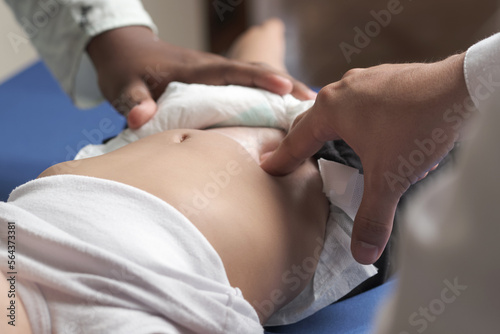 doctor's hands palpating unrecognizable baby's femoral pulse