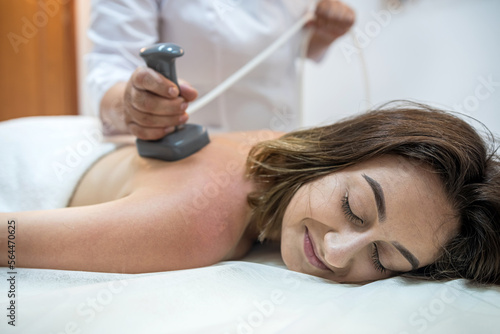 Body care procedure of woman lying on white sheets a masseuse massages female client in salon
