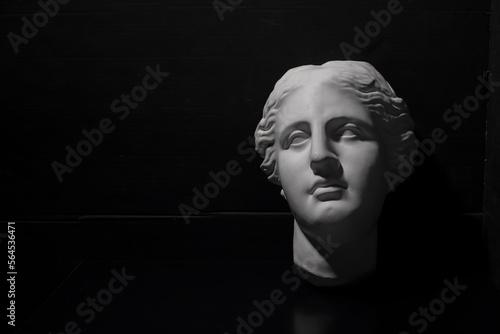 Greek style plaster face in a dark room, copy space. Thinking about