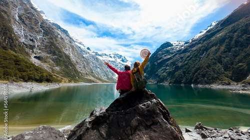  Travelers couple team look on the mountain landscape. Travel and active life concept as Adventure travel in the mountains region in lake marian fiordland national park