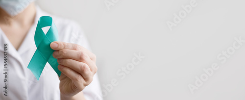 Doctor holds Teal ribbon on white background. Symbolic for cervical cancer, ovarian cancer, gynecological cancer and PCOS. And sexual assault awareness. Women's health care