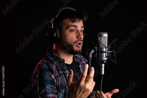 Hombre cantor grabando su voz con microfono de condensador y auriculares