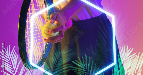 Midsection of biracial female tennis player with racket and ball by illuminated hexagon and plants