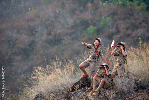 Three boy scouts exploring nature with binoculars in camp