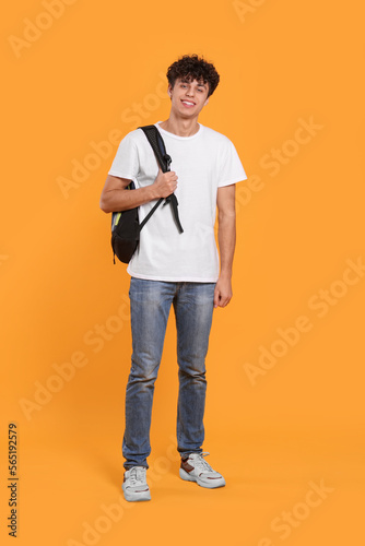Handsome young man with backpack on orange background