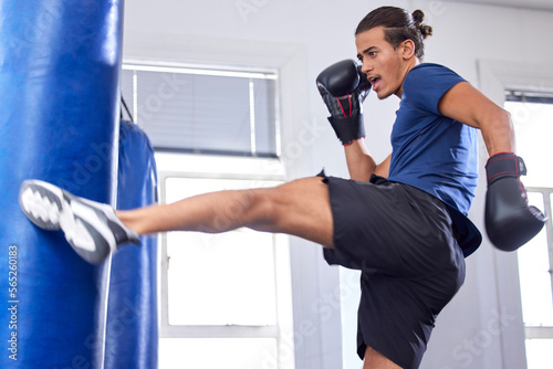 Kickboxing, fitness and sports with a man fighter training his power in a gym for a competition. Exercise, health and energy with a male kickboxer in a sport facility for a workout on a punching bag