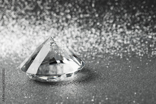 Beautiful dazzling diamond on shiny glitter background, space for text. Precious gemstone