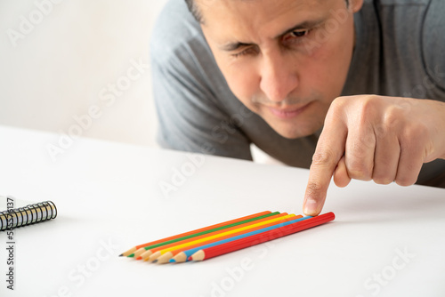 Obsessive compulsive man aligning up pencils on a table at office