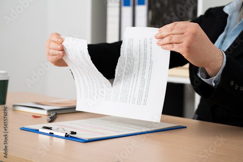 Close-up of the hands of a businesswoman tearing up the signed contract document sitting at a desk in the office