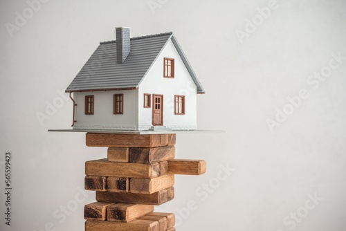 Modern house on wood tower block game white wall background copy space. Mortgage loan for buying home or real estate property, money risk management in financial, foreclosure and bankruptcy concept