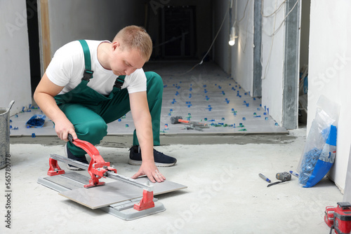 Worker using manual tile cutter in room