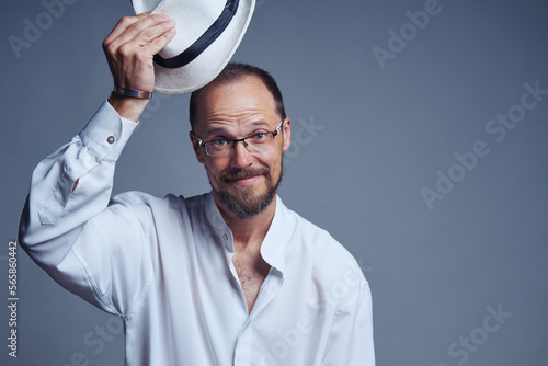 Smiling middle age man in straw hat lifting his hat welcoming