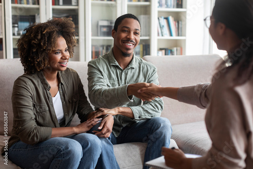 Happy african couple shaking family counselor hand, successful marital therapy
