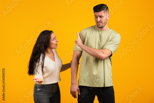 Angry dissatisfied young arab woman swears and yells at offended guy in casual, make stop sign with hand