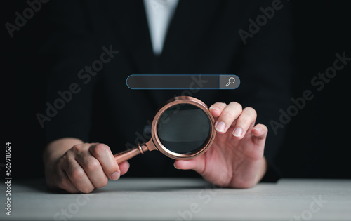 Businessman hand use magnifying glass Search On Virtual Screen Data Search Technology Search Engine Optimization. Searching for information. Using Search Console for data, info.