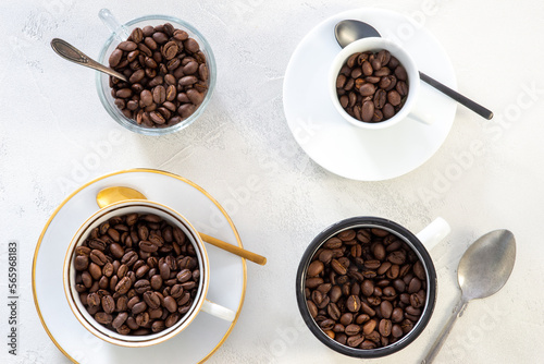 four different coffee cups filled with organic coffee beans, top view and white background
